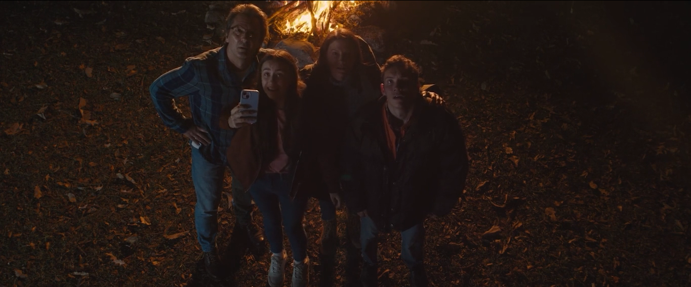 A family gathered around firelight at night in The Strange