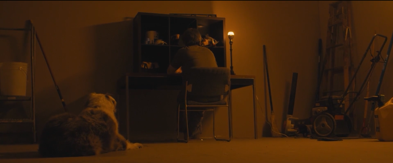 A figure at a desk in a dimly lit amber room in The Strange